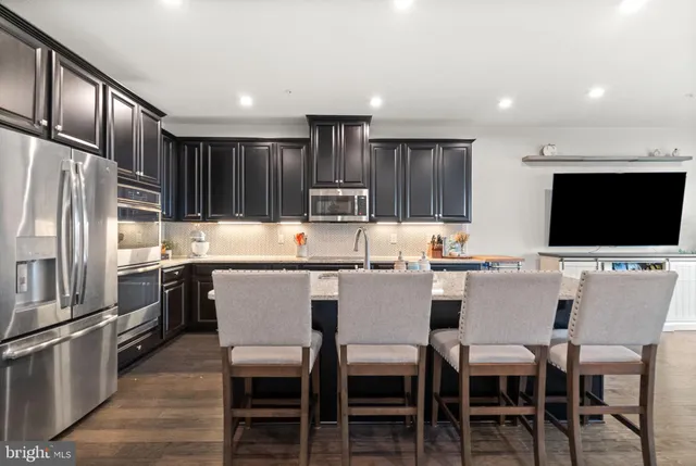 a kitchen with stainless steel appliances kitchen island granite countertop a table chairs microwave and sink