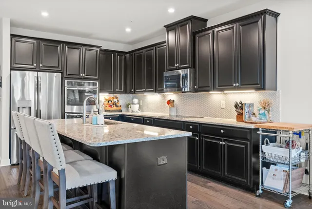 a kitchen with stainless steel appliances granite countertop a stove refrigerator sink and cabinets