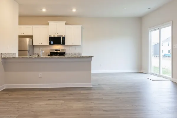 a view of kitchen with stainless steel appliances wooden floor and window