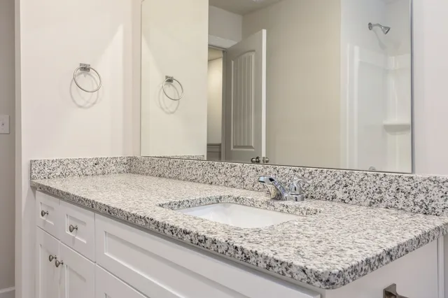 a bathroom with a granite countertop sink and a mirror