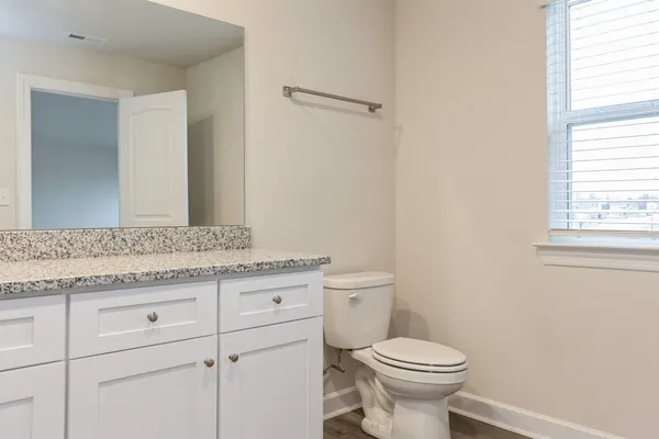 a bathroom with a granite countertop toilet a sink and a mirror