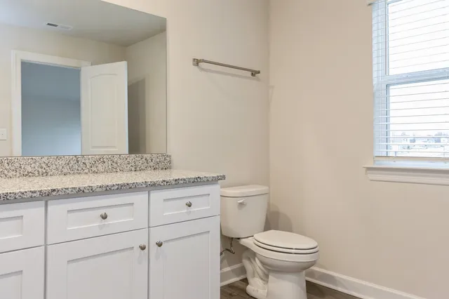 a bathroom with a granite countertop toilet a sink and a mirror