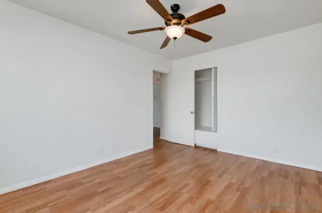 an empty room with wooden floor and a ceiling fan