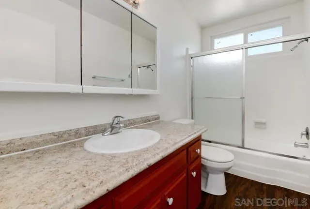 a bathroom with a granite countertop sink toilet and a mirror