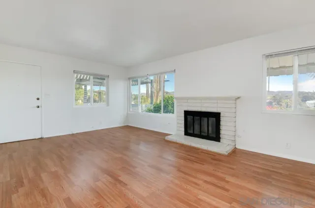 a view of empty room with wooden floor and fireplace