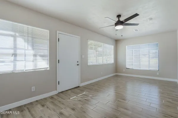 a view of an empty room with a window and wooden floor
