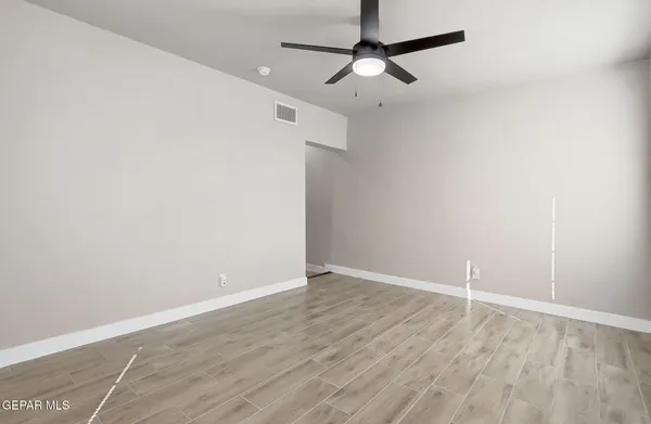 an empty room with wooden floor ceiling fan and window