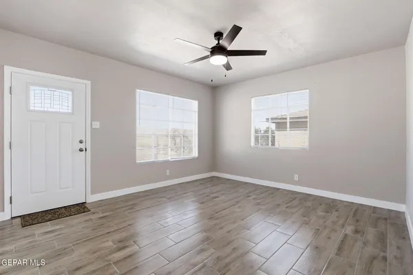 a view of an empty room with wooden floor and a window