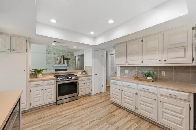 a kitchen with stainless steel appliances granite countertop a stove a sink and a refrigerator with wooden floors