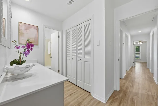 a view of a hallway with wooden floor and a bathroom