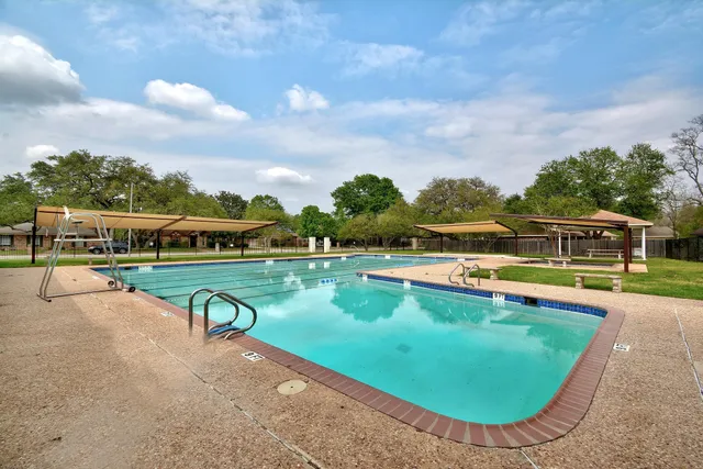 a view of a swimming pool with lawn chairs under an umbrella