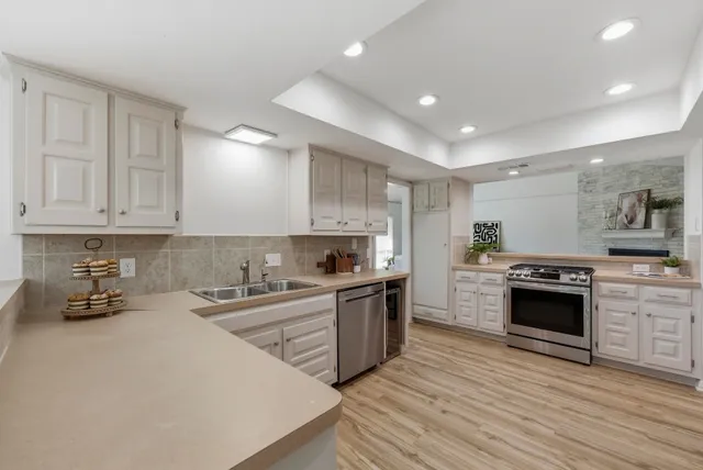 a kitchen with stainless steel appliances granite countertop a stove top oven a sink a counter space and cabinets