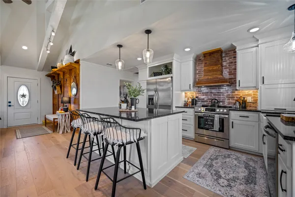 a kitchen with stainless steel appliances kitchen island granite countertop a table chairs in it and wooden floors
