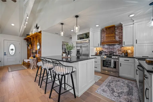 a kitchen with stainless steel appliances kitchen island granite countertop a table chairs in it and wooden floors