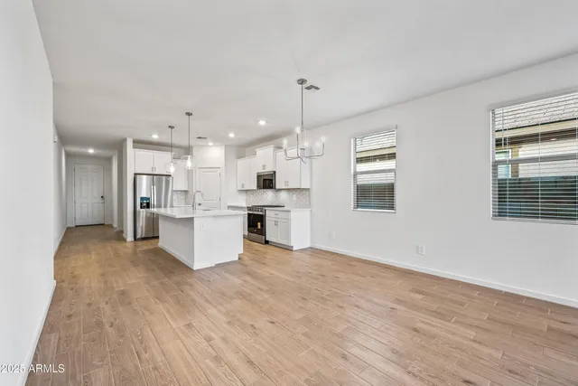 a large kitchen with kitchen island a stove a sink dishwasher and white cabinets with wooden floor