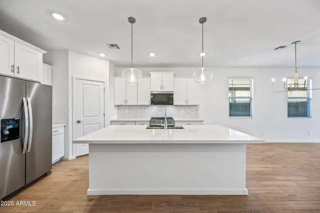 a large kitchen with granite countertop a large kitchen island white cabinets and stainless steel appliances