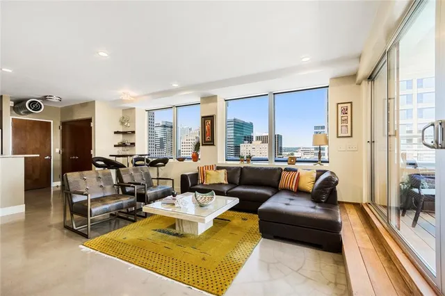 a living room with furniture floor to ceiling window hardwood floor and a flat screen tv