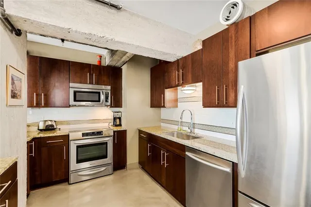 a kitchen with stainless steel appliances granite countertop a refrigerator and a stove