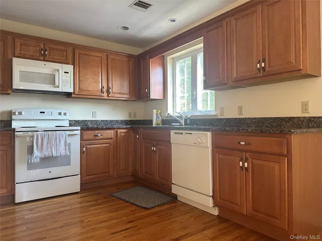 a kitchen with granite countertop wooden cabinets stainless steel appliances a sink and a window