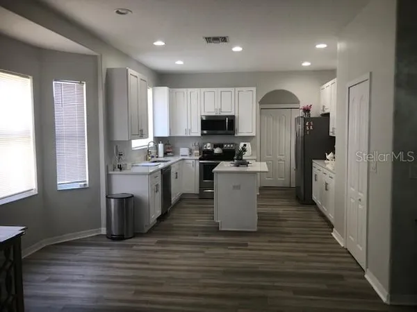 a kitchen with a sink a microwave a refrigerator and cabinets