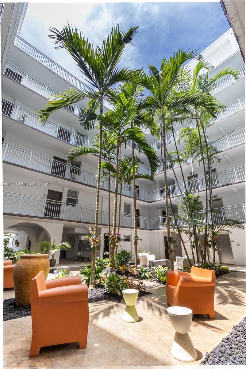 680 Northeast 64th Street, Unit A516 Miami, FL 33138 - Photo 53 of 54 a view of a patio with couches and chairs potted plants and palm tree