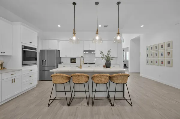 a kitchen with stainless steel appliances a dining table chairs refrigerator and sink