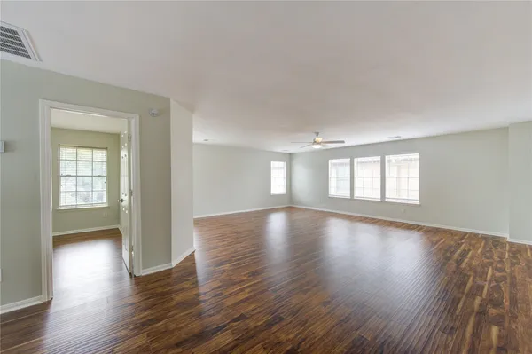 a view of empty room with wooden floor and fan