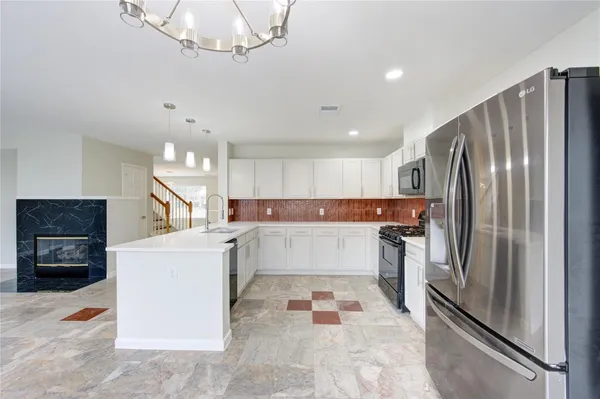 a white kitchen with stainless steel appliances granite countertop a refrigerator and a stove top oven