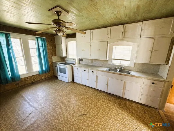 a large white kitchen with a large window appliances and cabinets