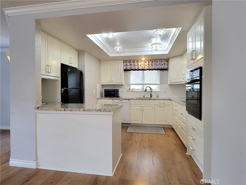 2082 Ronda Granada, Unit D Laguna Woods, CA 92637 - Photo 20 of 36 a kitchen with stainless steel appliances a refrigerator a sink dishwasher a stove and white cabinets with wooden floor