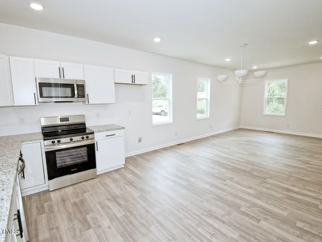 a kitchen with stainless steel appliances a stove top oven a sink dishwasher and a microwave oven on the wooden floor