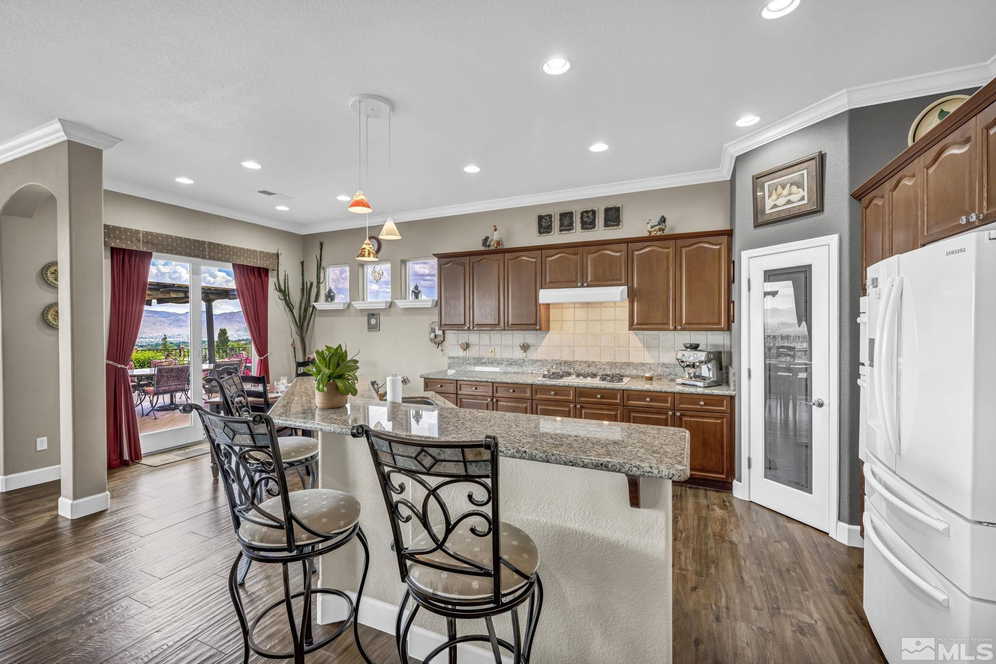 6824 Marble Canyon Road Reno, NV 89511 - Photo 10 of 30 a kitchen with stainless steel appliances kitchen island granite countertop a table chairs sink and cabinets