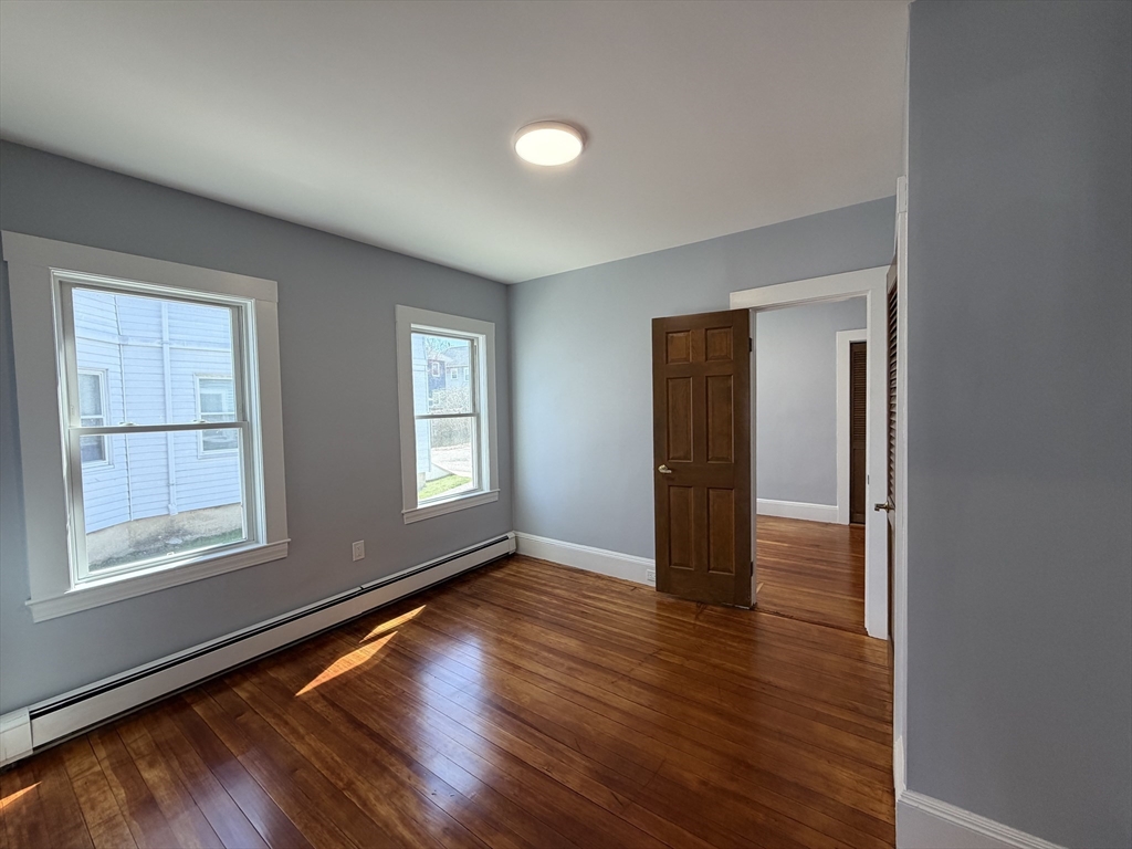 117 Merrymount Road, Unit 1 Quincy, MA 02169 - Photo 8 of 12 an empty room with wooden floor and windows