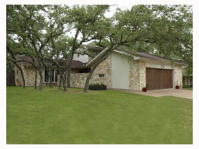 a backyard of a house with plants and large tree