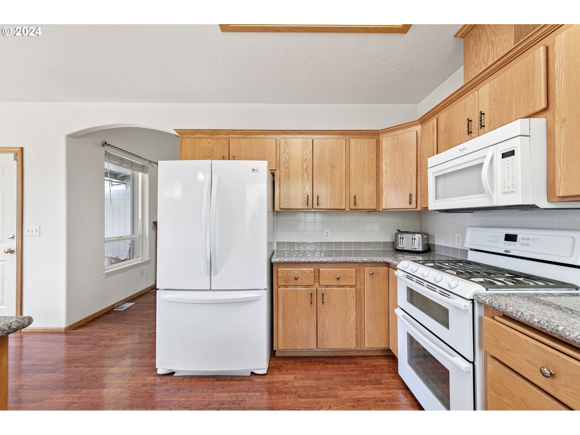 815 R Street Springfield, OR 97477 - Photo 20 of 37 a kitchen with stainless steel appliances granite countertop a refrigerator a stove a sink and white cabinets with wooden floor