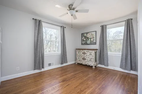 a view of an empty room with a window and wooden floor