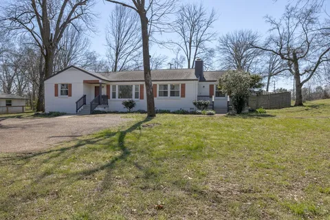 a view of a yard in front of a house with large trees