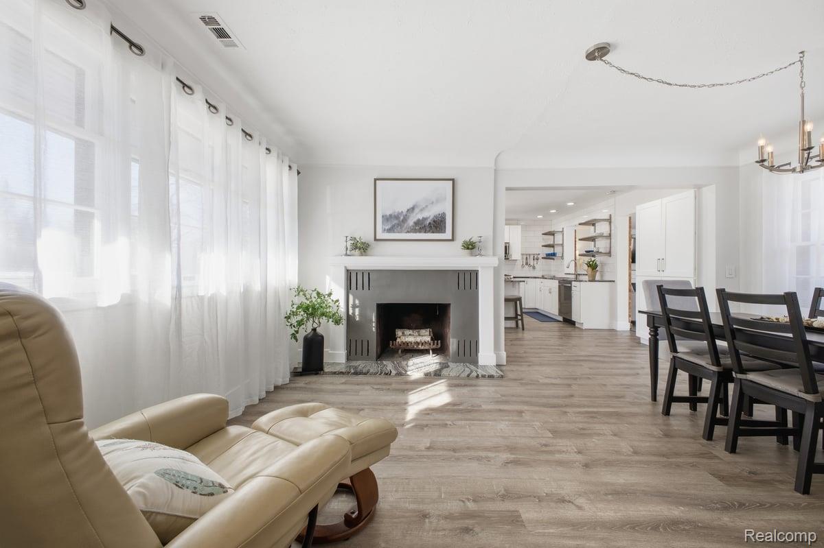 Living room featuring light wood-type flooring, a fireplace, and suspended lighting