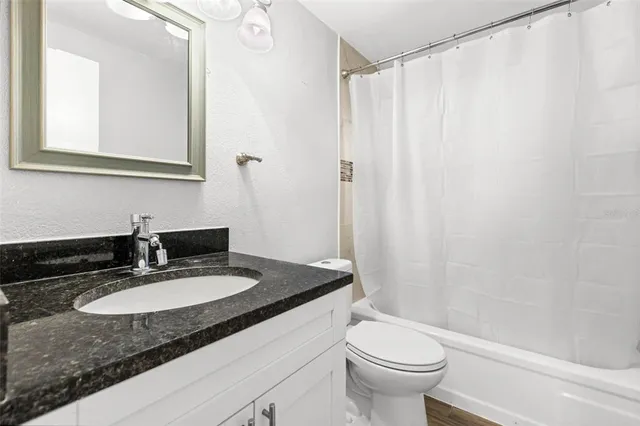 a bathroom with a granite countertop sink toilet and a mirror
