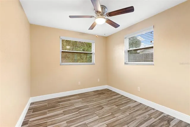 a view of empty room with wooden floor and fan