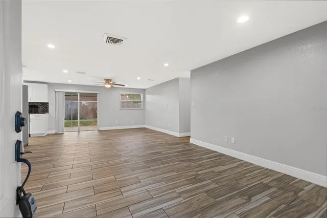 a view of an empty room with wooden floor and windows