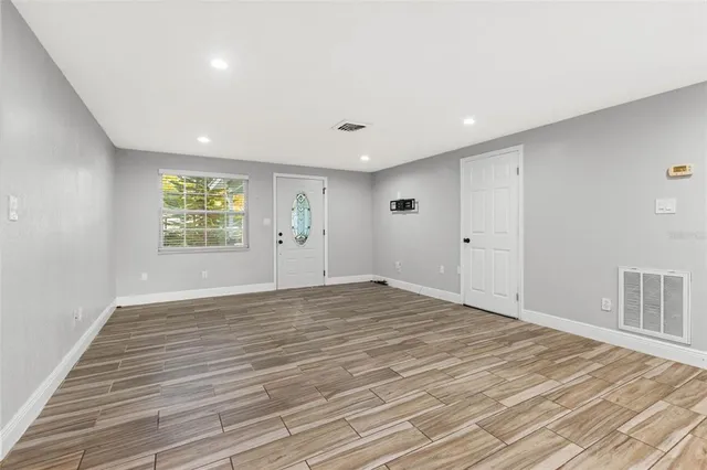 a view of empty room with wooden floor and fan