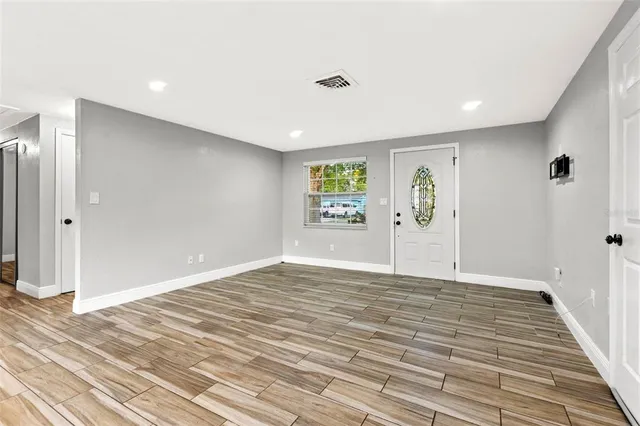 a view of an empty room with wooden floor and a window