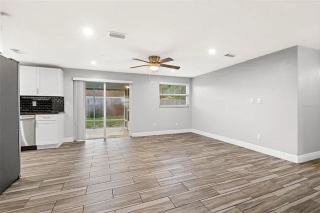 a view of an empty room with a window and wooden floor