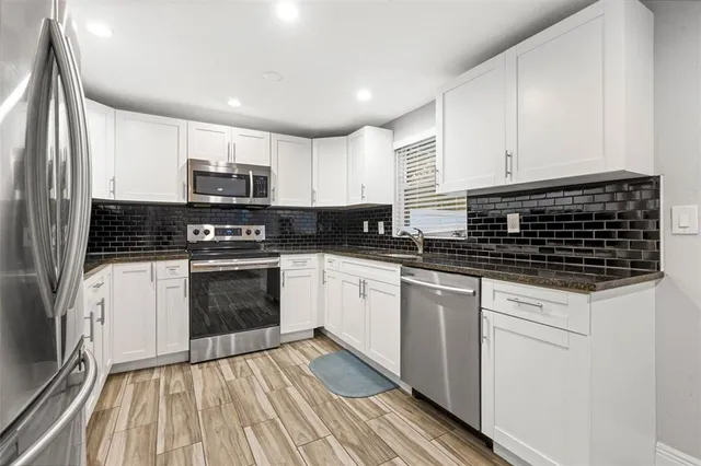 a kitchen with granite countertop a sink cabinets stainless steel appliances and a counter space