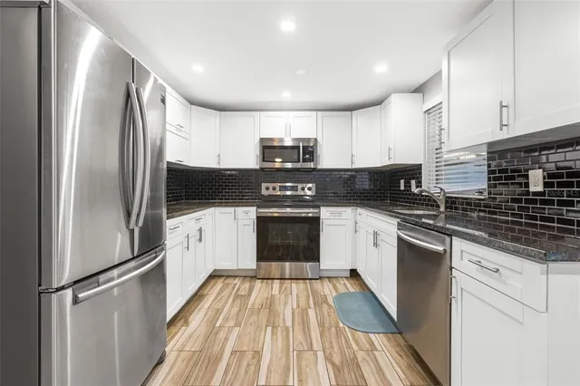 a kitchen with granite countertop a refrigerator stove top oven and sink