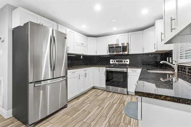 a kitchen with granite countertop a refrigerator stove and sink