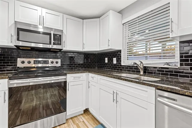 a kitchen with stainless steel appliances granite countertop a sink a stove and microwave