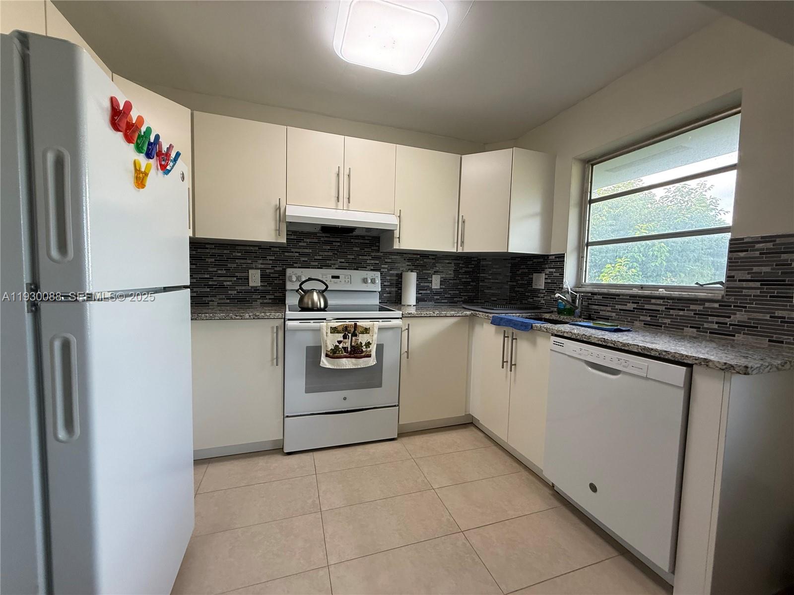 900 Tallwood Avenue, Unit 306 Hollywood, FL 33021 - Photo 5 of 30 a kitchen with a refrigerator a stove top oven a sink and a window