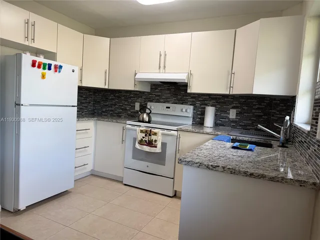 a kitchen with granite countertop a white stove and white cabinets